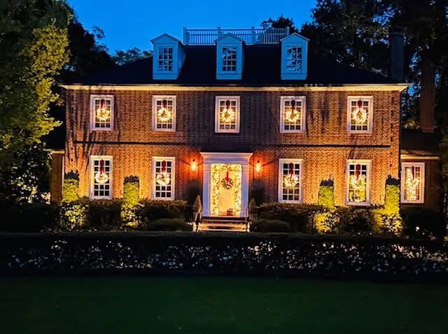 Brick colonial home lit warmly with wreaths
