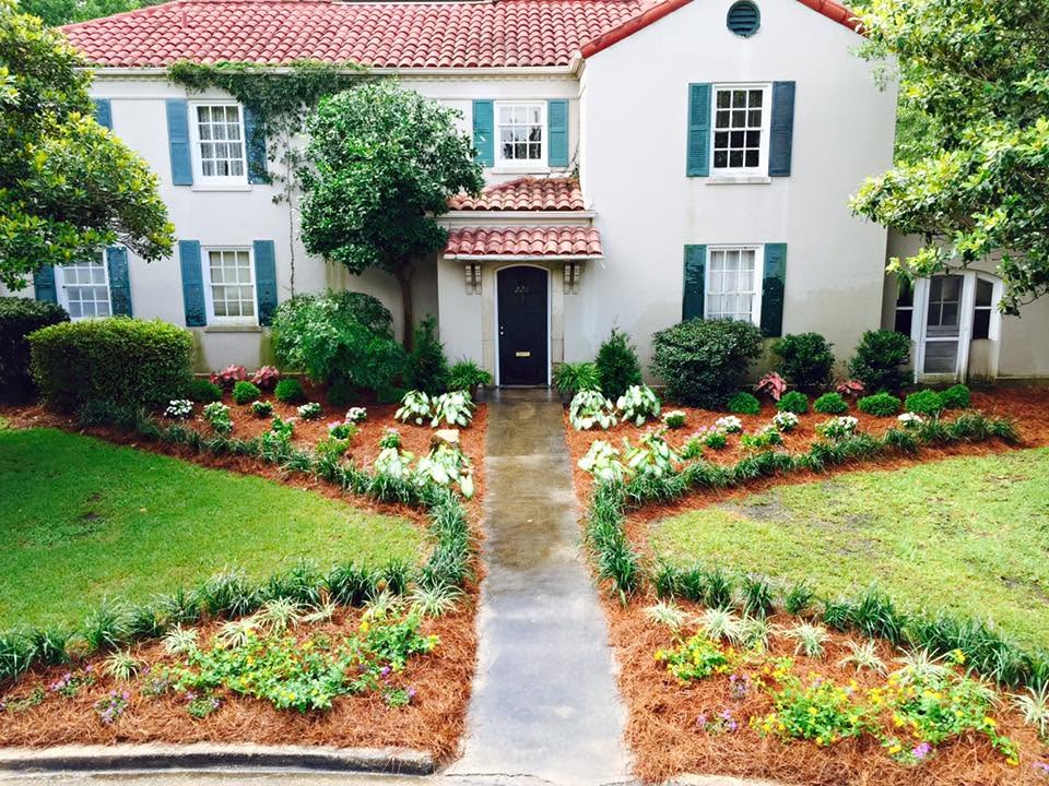 Same commander's house after film-preparation landscaping, with fresh pine straw, ornamental grasses, shrubs, and a more finished front approach